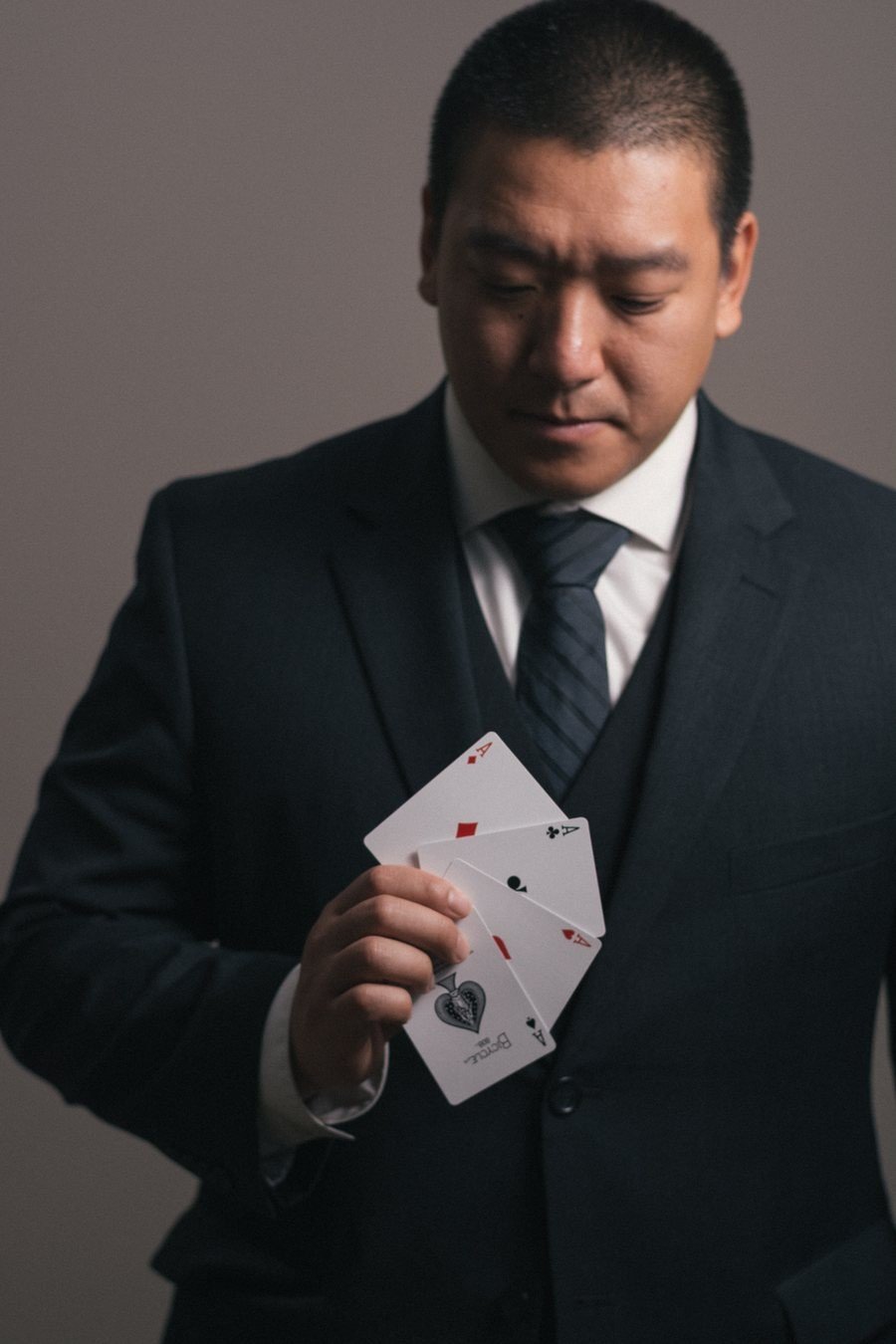 John Ha in formal attire holding playing cards