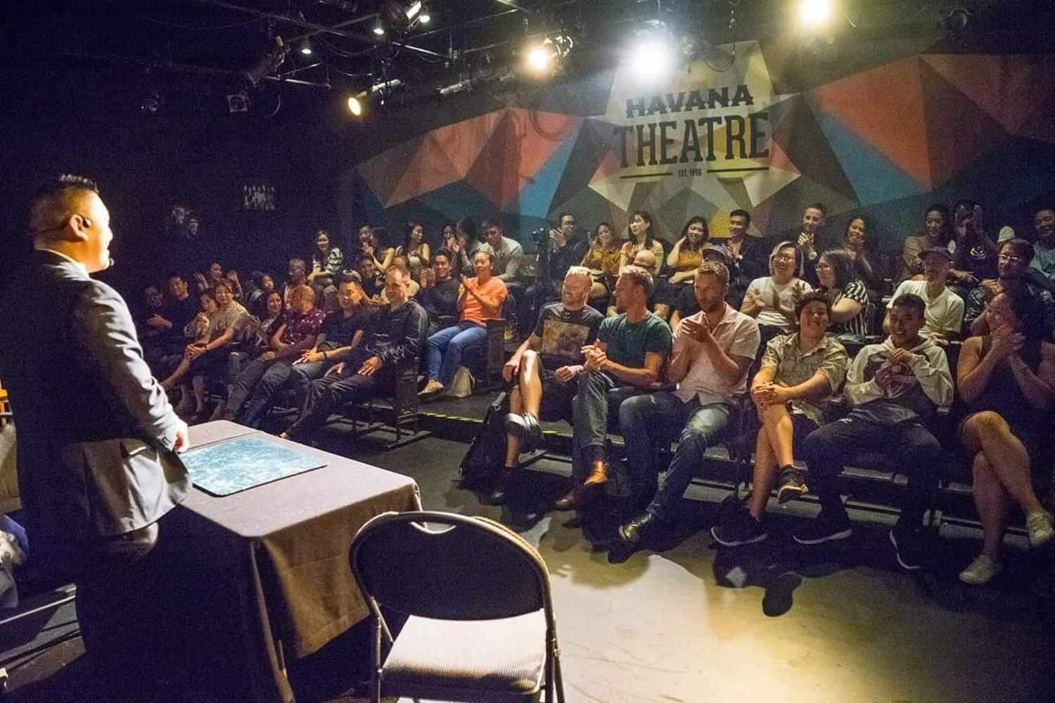 John Ha performing a stand-up magic show for a seated audience