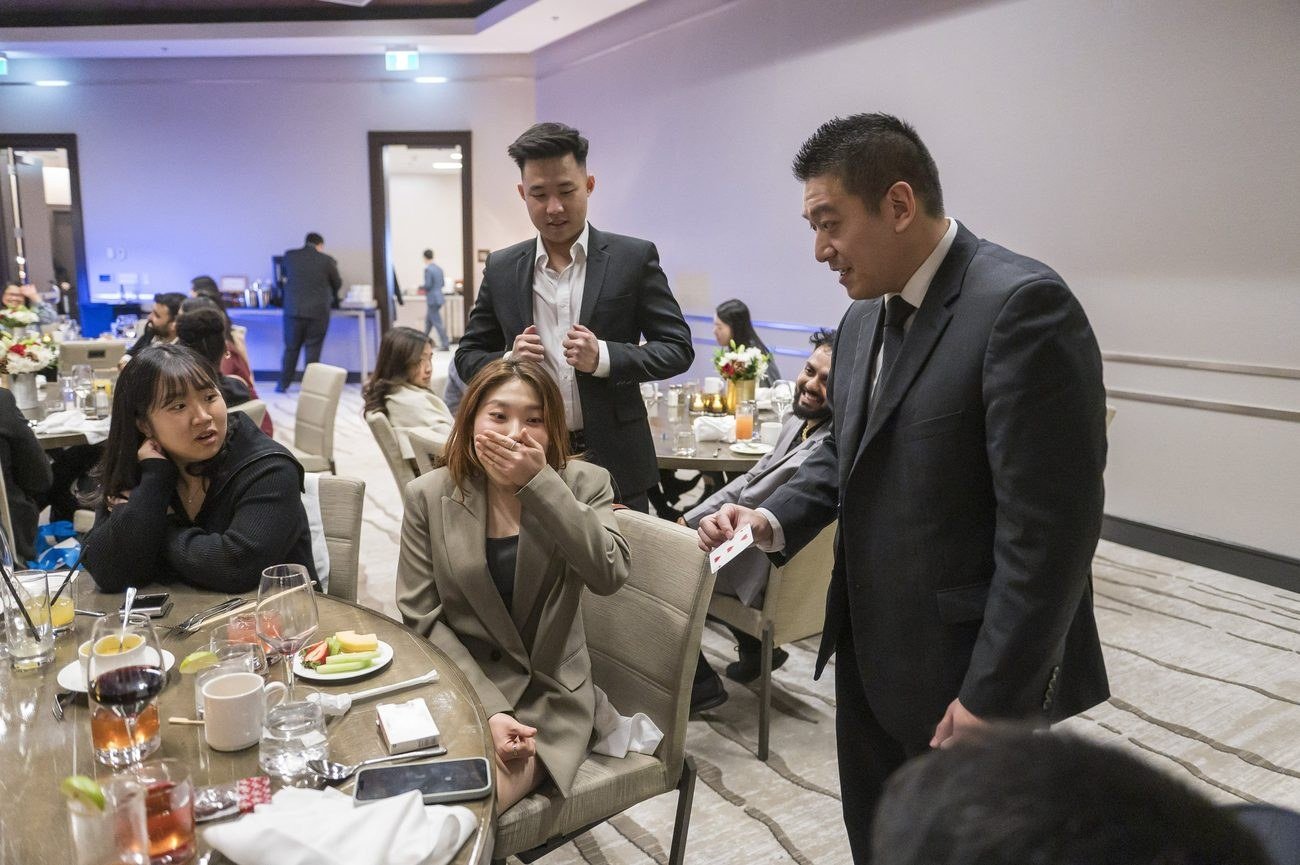 John Ha performing close-up magic for guests at a Vancouver open house style event