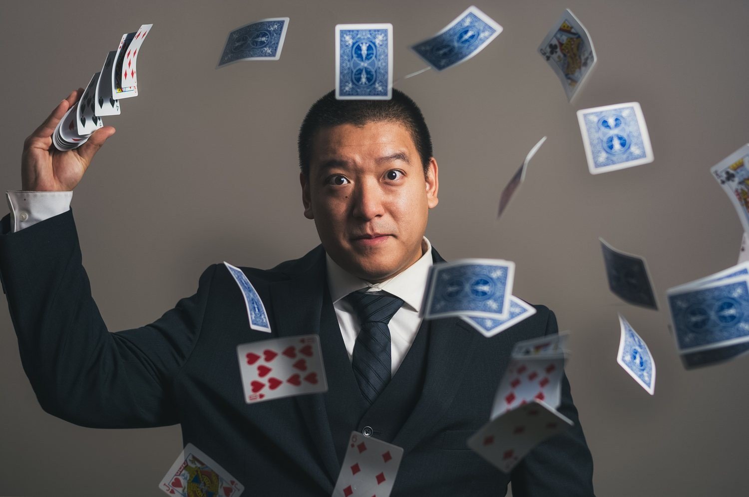 John Ha surrounded by playing cards in a polished magic portrait