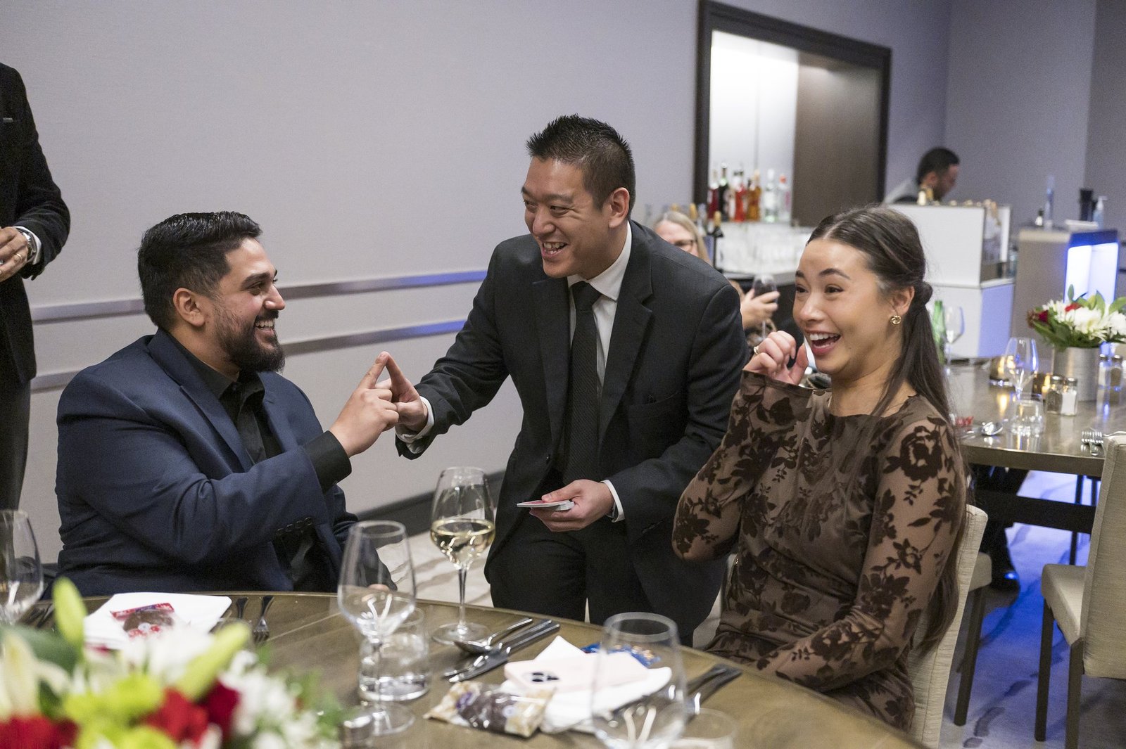 John Ha performing close-up magic for guests at a corporate dinner table